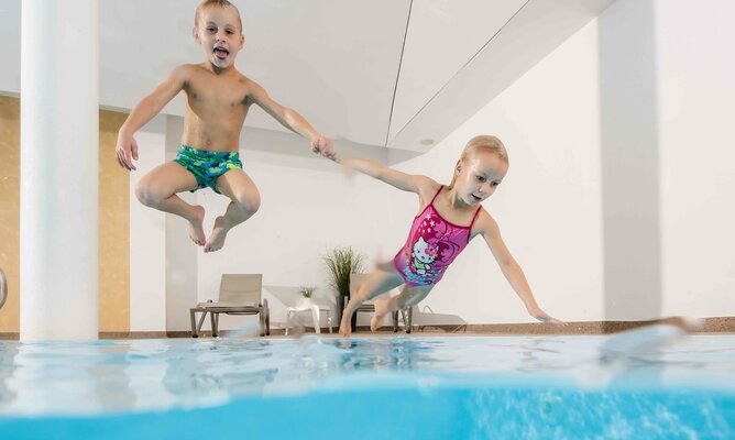 Kinder springen ins Schwimmbecken