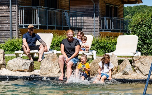 Familie sitzt am Badeteich