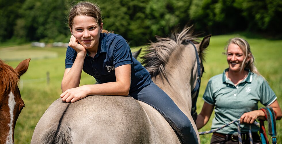 Mädchen sitzt verkehrt am Rücken eines Pferdes Mädchen sitzt verkehrt am Rücken eines Pferdes