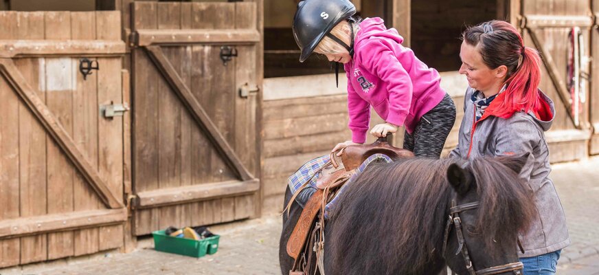 Mädchen steigt aufs Pony