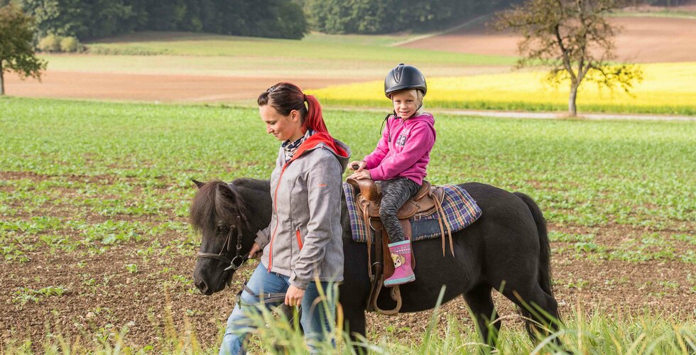 Reitlehrerin beim Ausritt mit Kind