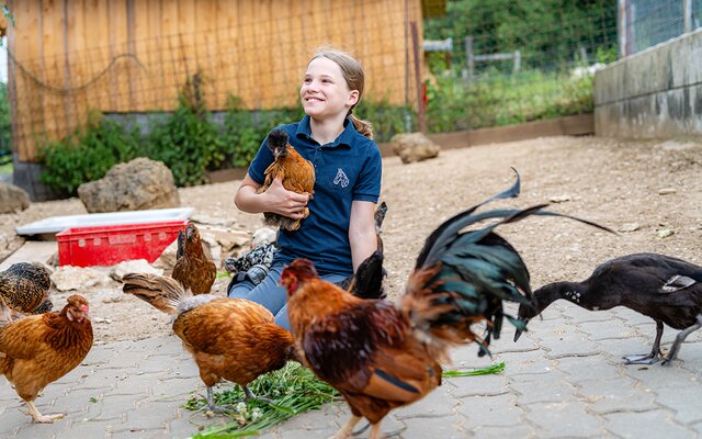Mädchen hält Huhn in der Hand und lächelt